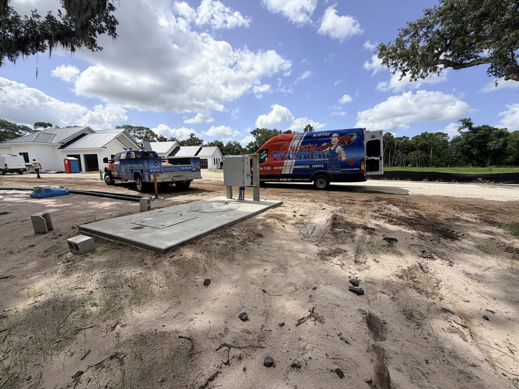 County Plumbing van and service truck at a lift-station job site